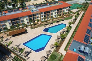 Un hotel con dos piscinas, varios balcones y una azotea con paneles solares.