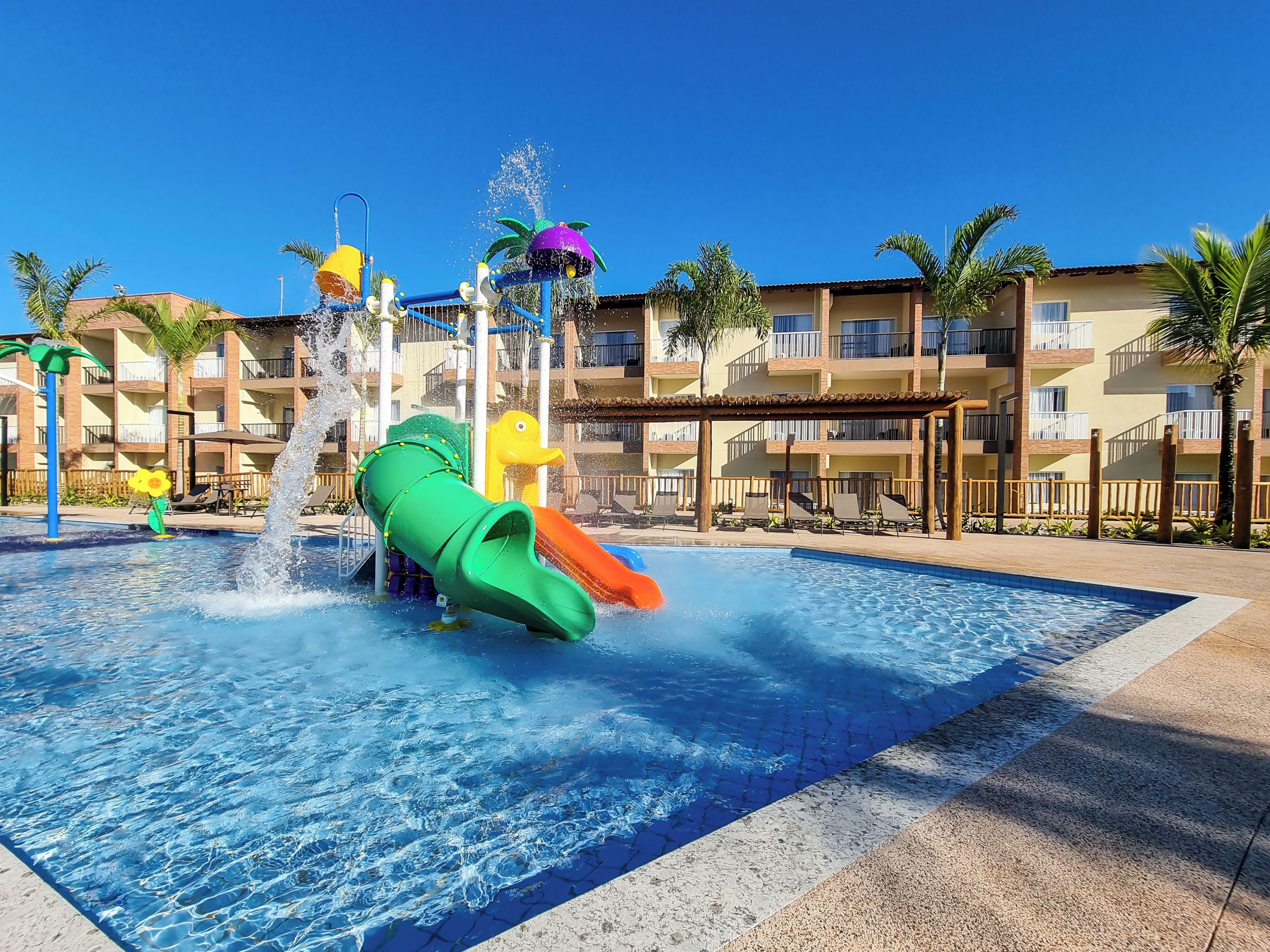 Un parc aquatique doté de toboggans et d’une zone de piscine, entouré d’un immeuble à plusieurs étages avec des balcons.