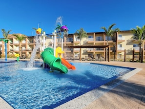 A water park with slides and a pool area, surrounded by a multi-story building with balconies. - Ondas Praia Resort by WAM Experience (Porto Seguro)