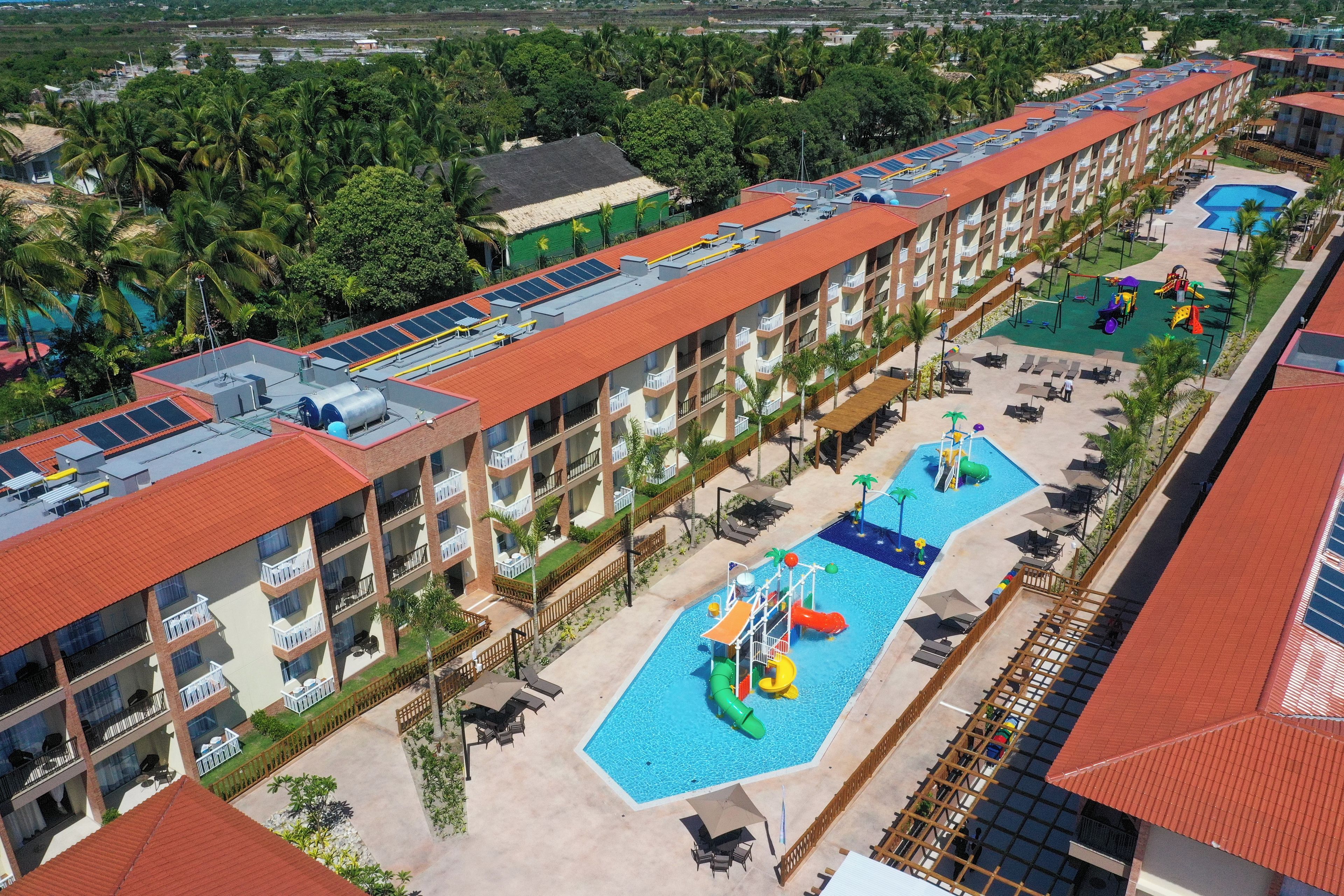 A hotel with multiple swimming pools, a water park, and a rooftop with solar panels.