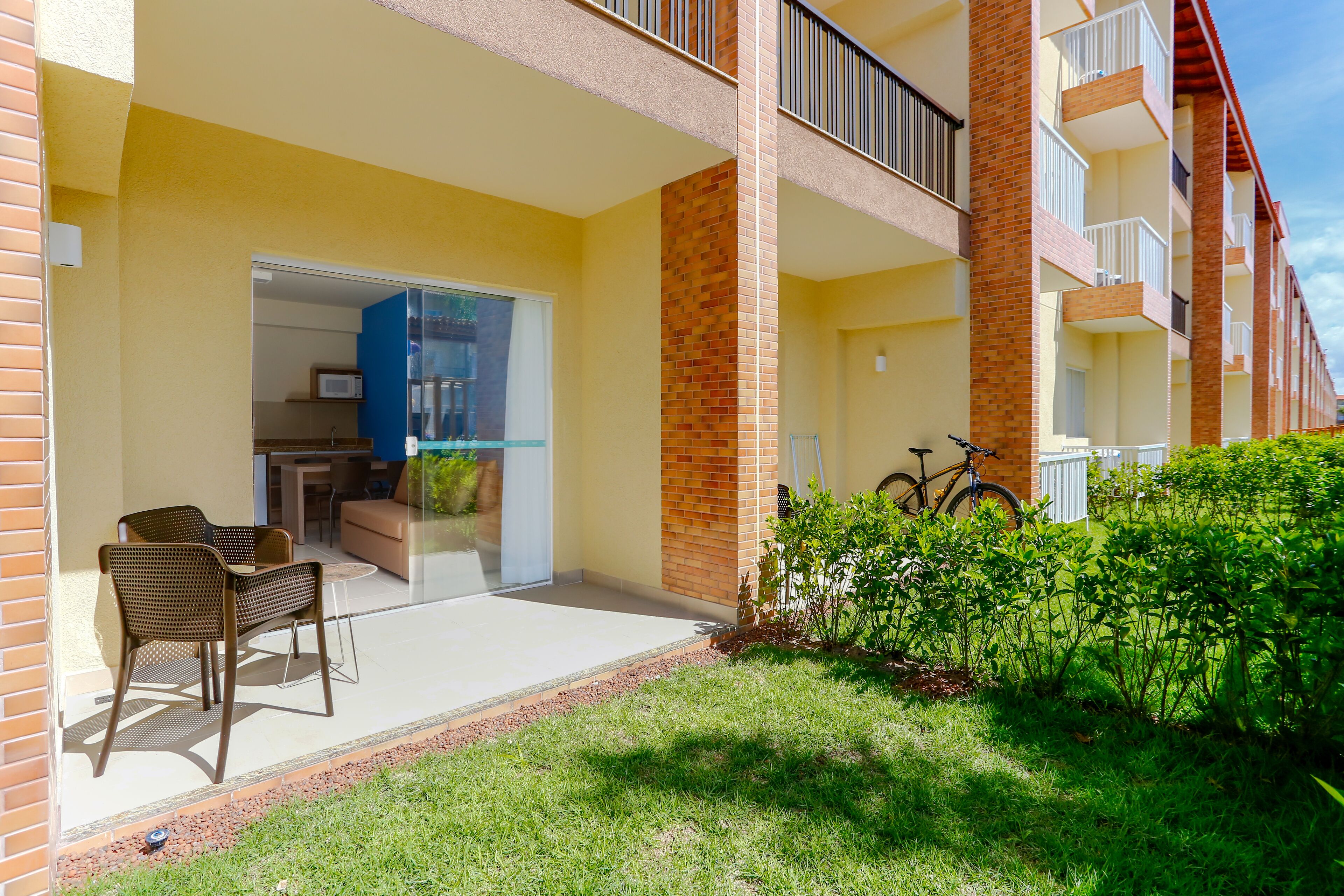 A residential building with a patio area featuring outdoor furniture, a bicycle, and a small garden.