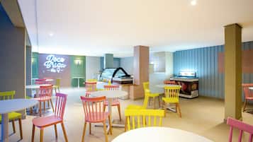 A brightly lit indoor space with multiple tables and chairs, a neon sign, and a vending machine.