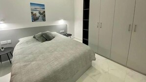Un dormitorio con cama, mesitas de noche, armario y un cuadro en la pared.