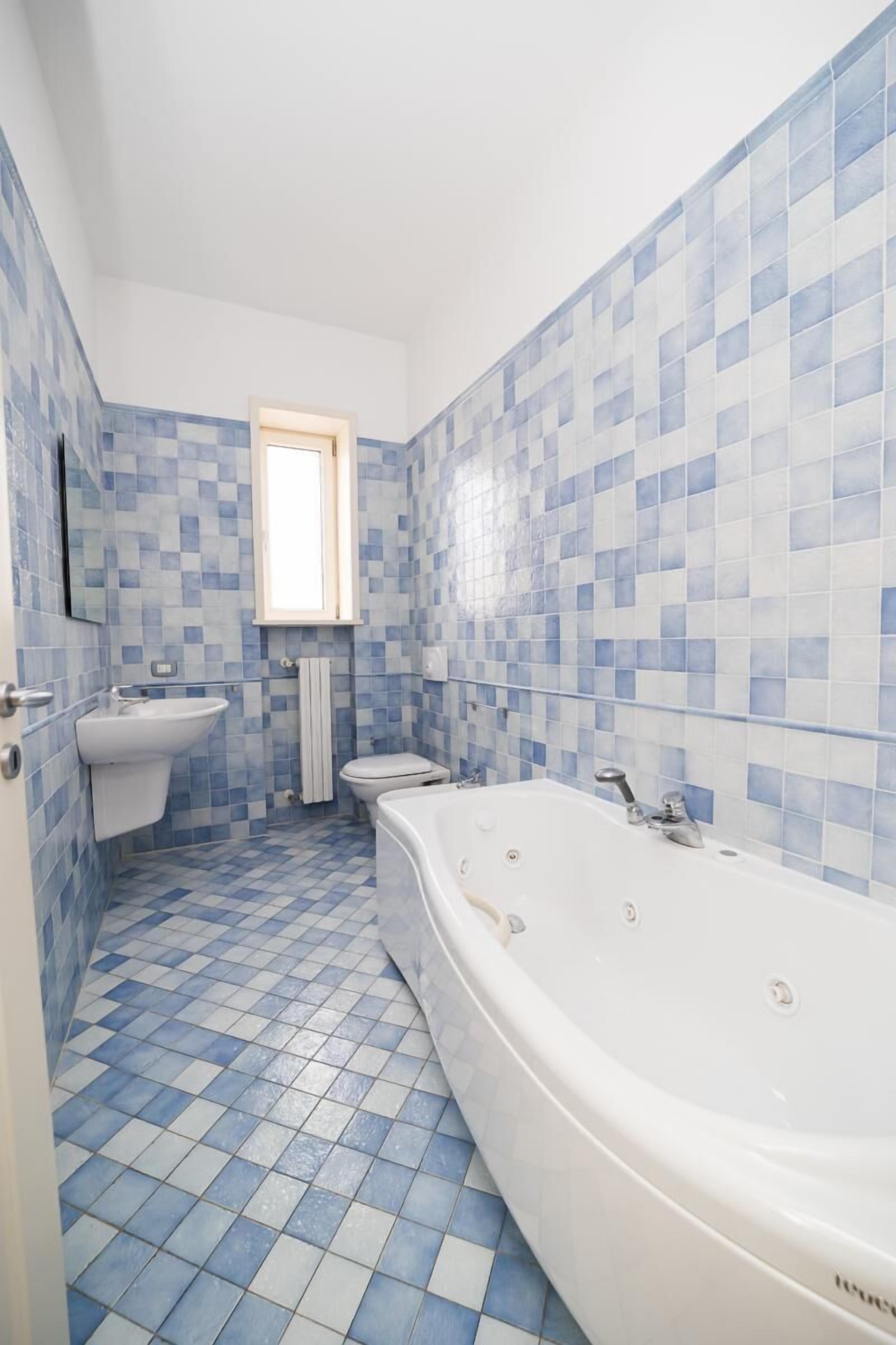 Un bagno con pavimento a scacchi, una vasca, un lavandino e un water.