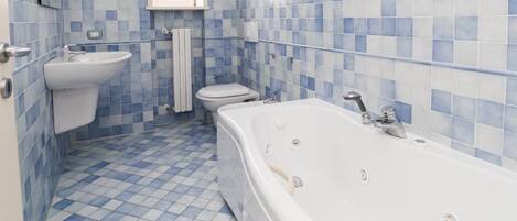 Un bagno con pavimento a scacchi, una vasca, un lavandino e un water.