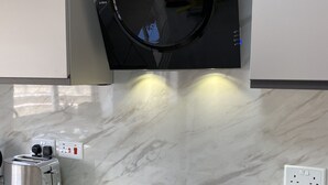 Uma cozinha com micro-ondas integrado, torradeira e fogão por indução preto.