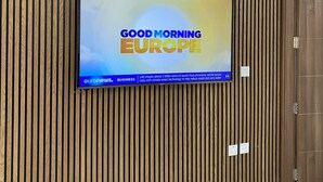 Televisão fixada na parede com painel de madeira.