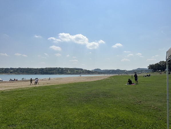 A grassy area with a beach and water in the background.