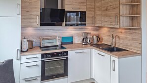 A modern kitchen with white cabinets, a built-in oven, a microwave, and a coffee maker. - 2 bedroom gorgeous home in Tossens (Tossens)