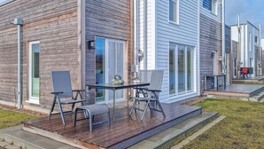A modern house with a wooden deck, two chairs, and a table. - 2 bedroom gorgeous home in Tossens (Tossens)