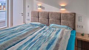 A bedroom with a bed, striped bedding, a headboard with wall-mounted lights, a window, and a small plant. - 2 bedroom gorgeous home in Tossens (Tossens)