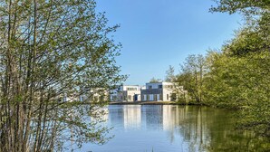 A modern building with a reflective water body in front, surrounded by trees. - 2 bedroom gorgeous home in Tossens (Tossens)