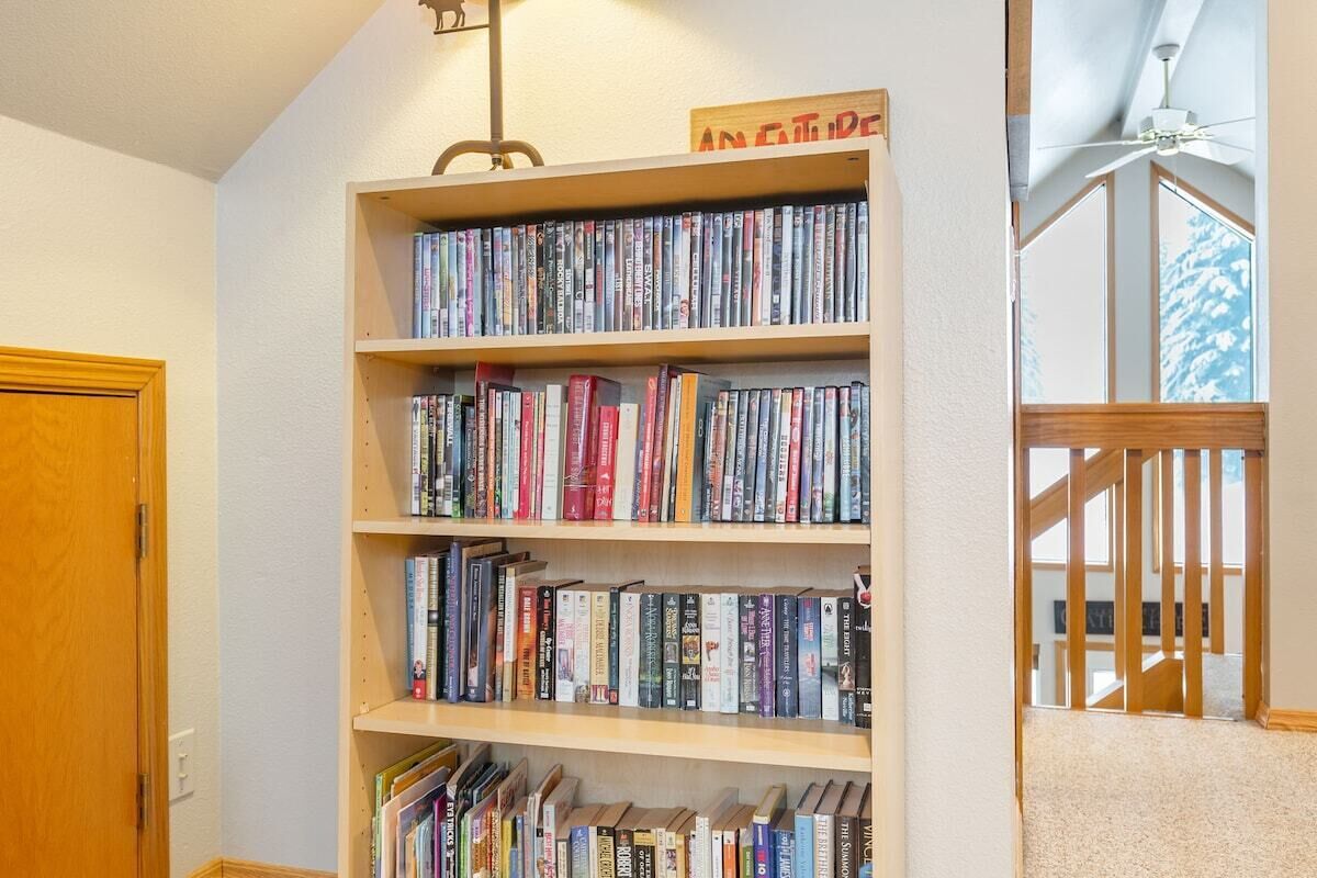 En bokhylla full av böcker, en trädörr och en trappa med ett räcke.