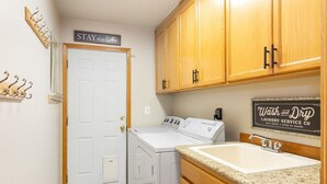 A compact laundry room with a washing machine, dryer, and a sink.