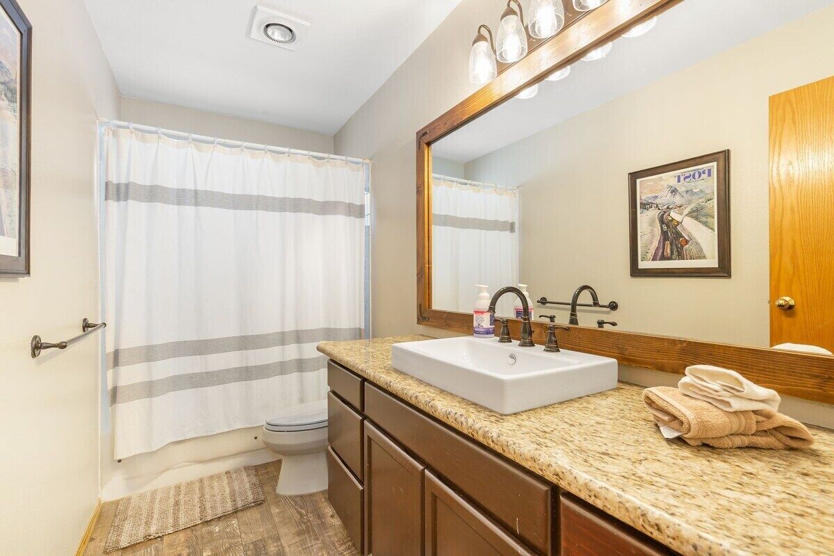 Une salle de bain avec un lavabo blanc, un meuble-lavabo en bois et un grand miroir.