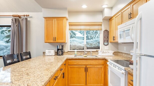 A kitchen with granite countertops, wooden cabinets, a built-in oven, and a microwave.