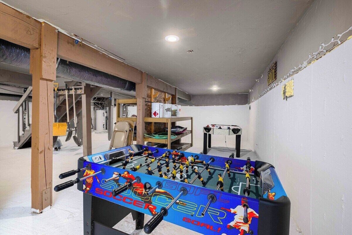 A room with a foosball table, exercise equipment, and a staircase.