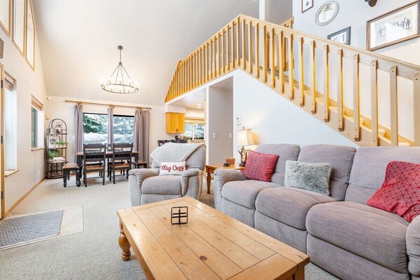 A living room with a grey sofa, a wooden coffee table, and a staircase with wooden railings.