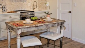 A kitchen with a rustic table, a stove, and a herringbone-patterned backsplash. - Chic View Loft at Historic Plaza - Spacious 470 Sq Ft (Santa Fe)