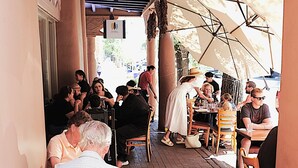 A covered outdoor seating area with brick flooring and wooden chairs. - Chic View Loft at Historic Plaza - Spacious 470 Sq Ft (Santa Fe)