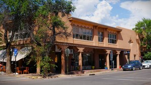 A two-story building with a flat roof and large windows. There is a parking sign and a stop sign visible. - Chic View Loft at Historic Plaza - Spacious 470 Sq Ft (Santa Fe)