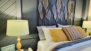 A neatly made bed with striped bedding, a decorative wall panel, and two bedside tables with lamps and a small sign. - Amazing Views! 2 BR 8-person Condo Lake Tomahawk/Minocqua Chain, Dock included (Lake Tomahawk)