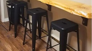 A bar area with a wooden counter and four black stools. - Amazing Views! 2 BR 8-person Condo Lake Tomahawk/Minocqua Chain, Dock included (Lake Tomahawk)