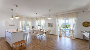 Une cuisine spacieuse dotée d’un îlot central, d’un coin repas avec des chaises et d’une table de baby-foot.