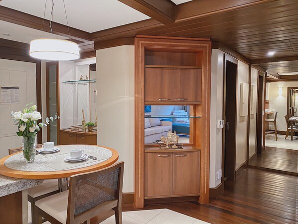 A dining area with a round table, chairs, a vase of flowers, and a wooden cabinet with glass shelves.