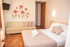 Una habitación de hotel con una cama, un sofá, un televisor montado en la pared y una puerta.