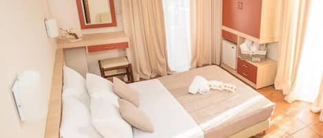 A hotel room with a bed, a desk, a chair, a mirror, and a wardrobe.