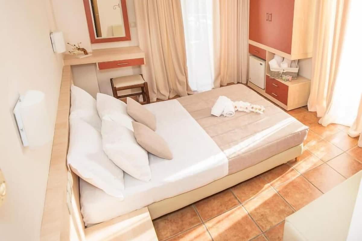 Una habitación de hotel con cama, escritorio, silla, espejo y armario.
