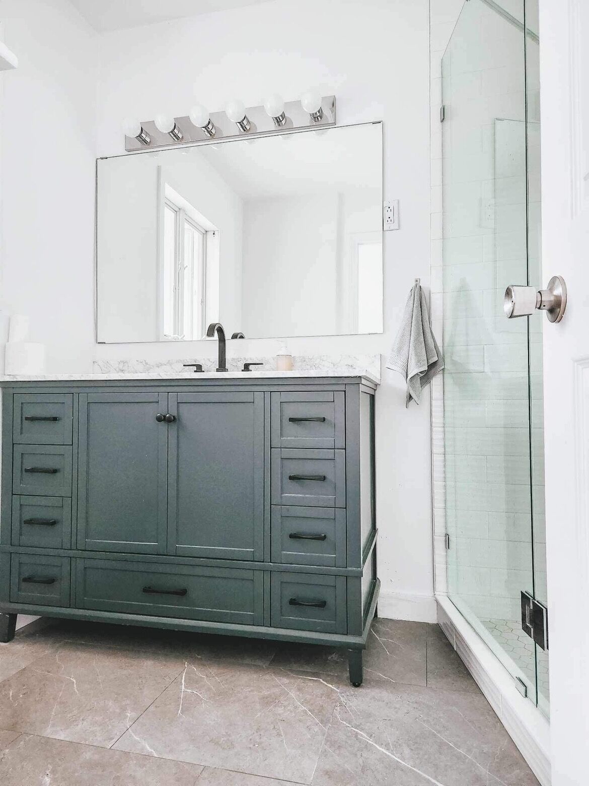 A bathroom with a vanity, a mirror, and a glass shower enclosure.