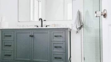 A bathroom with a vanity, a mirror, and a glass shower enclosure.