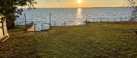 Un parc situé au bord de l’eau, avec une pelouse, une clôture en métal et un lampadaire.