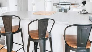 A modern kitchen with white cabinets, a central island with stools, and a built-in oven.