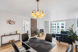 A modern living room with a dining area, large windows, and a view of the city. - Miami Building - MetroMover Access - We Host (Miami)