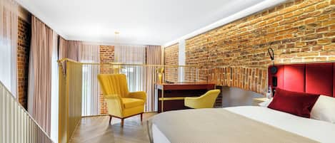 Une chambre moderne avec un mur en briques, un lit, un bureau et un fauteuil jaune.