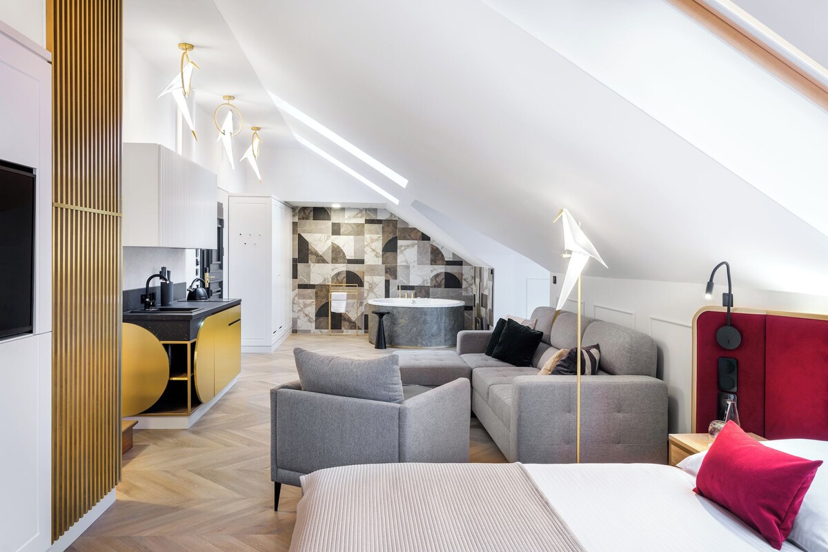 A modern loft bedroom with a large bed, a sofa, and a dining area.