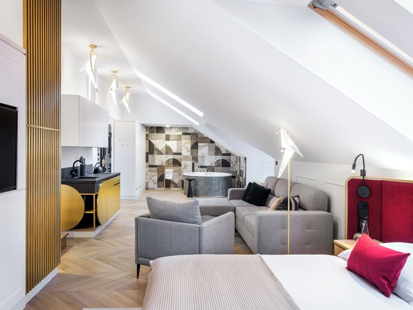 A modern loft bedroom with a large bed, a sofa, and a dining area. - Hotel Golden Queen (Kraków)