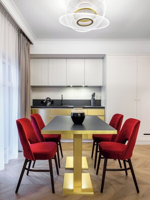 A modern dining area with a rectangular table, six red chairs, and a central black vase. - Hotel Golden Queen (Kraków)