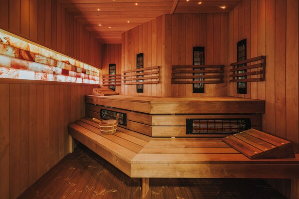 A sauna with wooden benches and walls, featuring built-in benches and windows. - Hotel Golden Queen (Kraków)