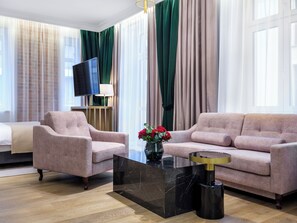 A modern living room with a sofa, armchair, and a coffee table. - Hotel Golden Queen (Kraków)