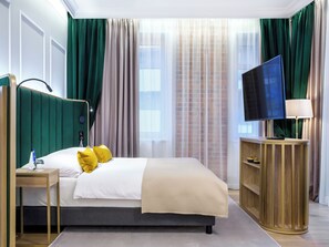A hotel room with a bed, a television, a bedside table, and a lamp. - Hotel Golden Queen (Kraków)