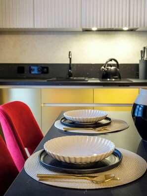 Una cocina moderna con encimera negra, una tetera y una silla roja.