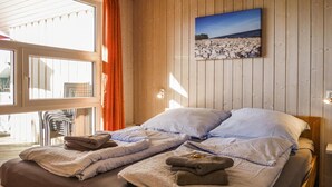 Habitación con paneles de madera, una cama, almohadas y toallas.