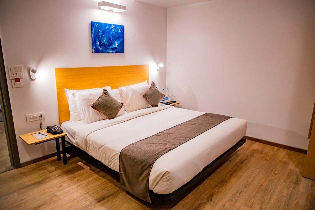 Een hotelkamer met een bed, nachtkastje en een kunstwerk aan de muur.