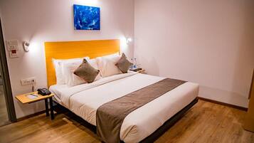 Een hotelkamer met een bed, nachtkastje en een kunstwerk aan de muur.