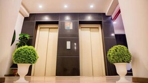 A hotel lobby with a reception desk, a large wooden door, and two potted plants. - Goldenkeys Inn (New Delhi)