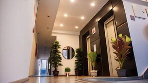 A hotel lobby with a polished floor, a reception desk, potted plants, and a large mirror on the wall. - Goldenkeys Inn (New Delhi)